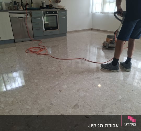אדם מנקה רצפה במכונת פוליש במטבח